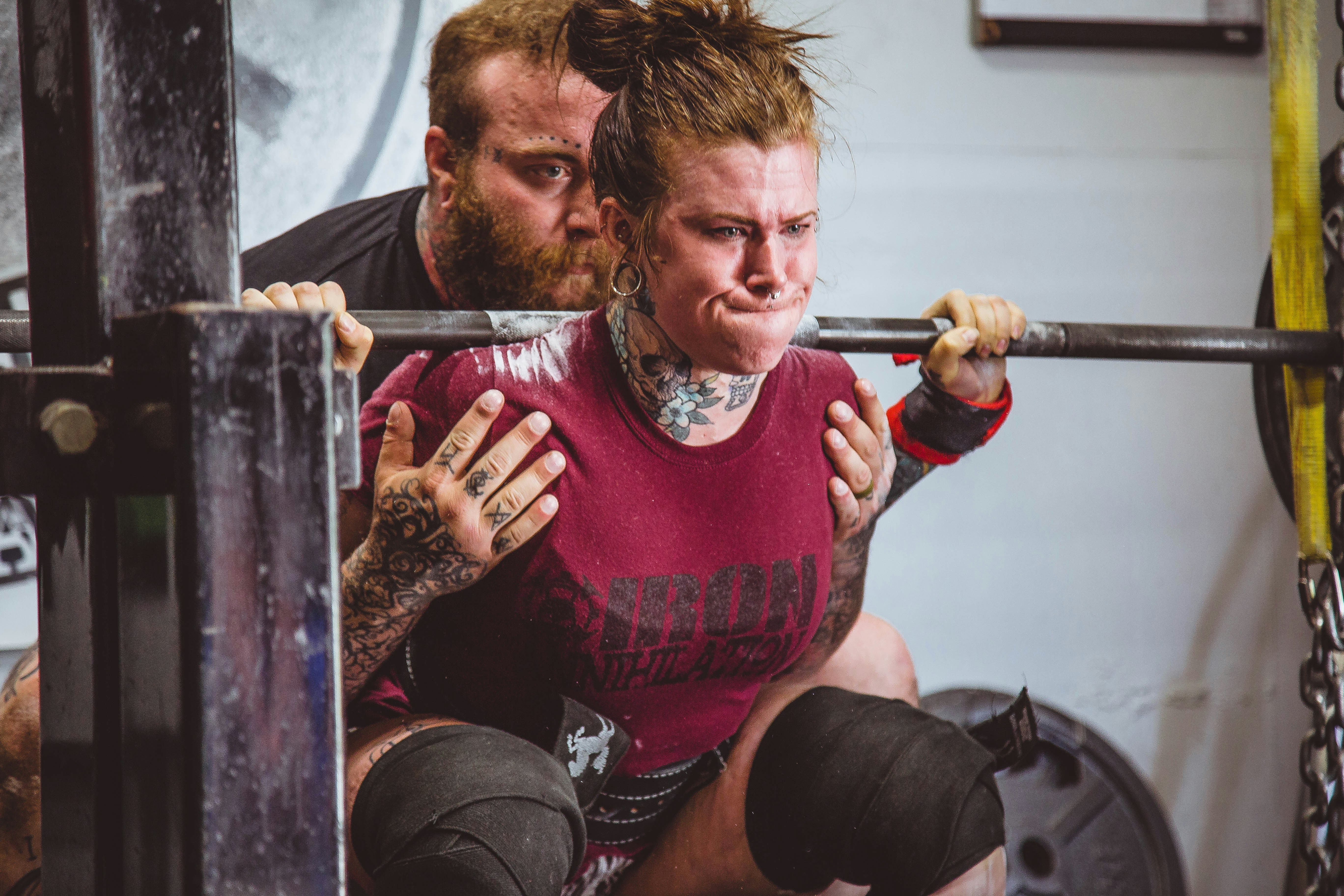 Lady being helped to do a power lift squat